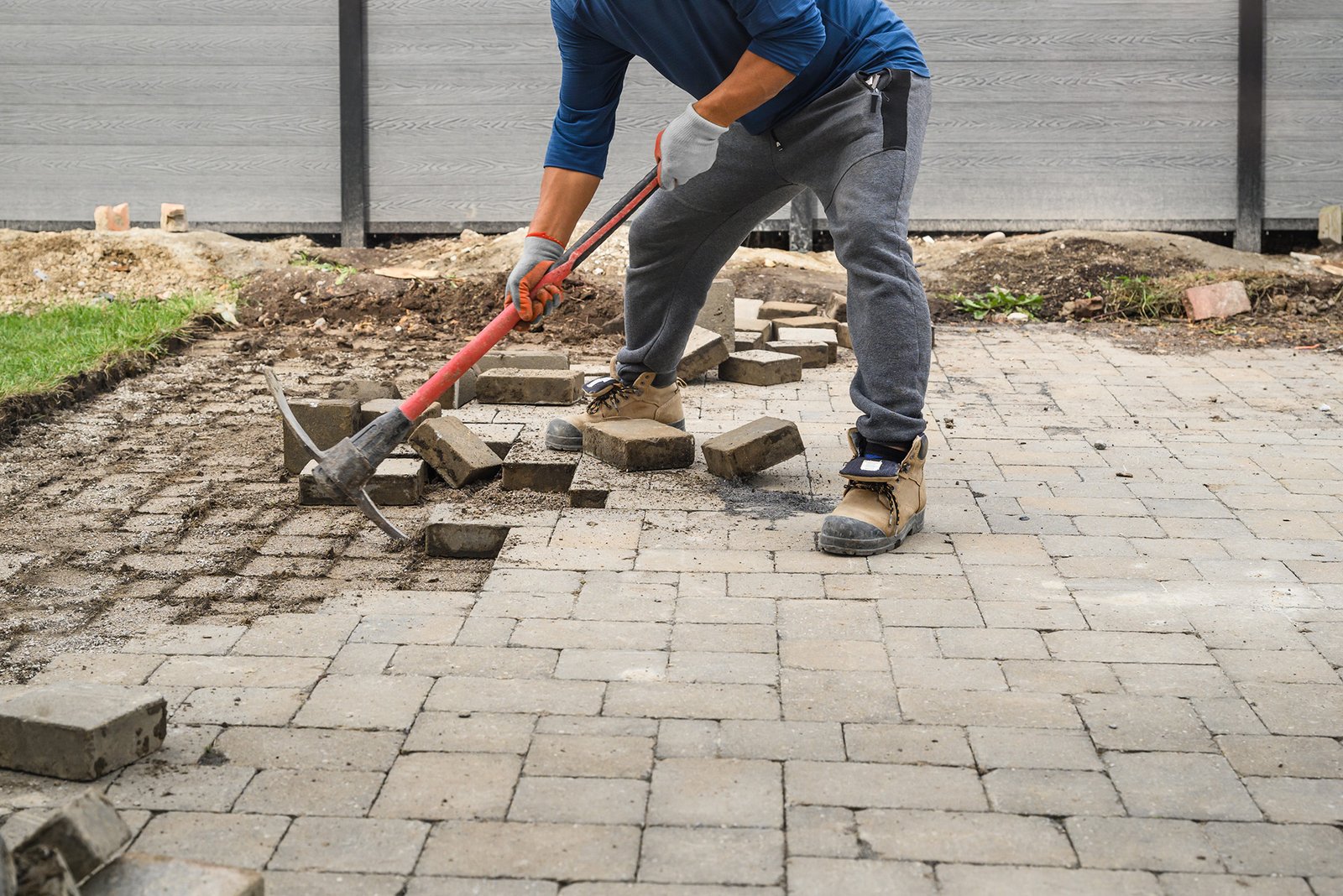 Man Loosening Pavers with Pick Mattock Man Loosening Pavers with Pick Mattock